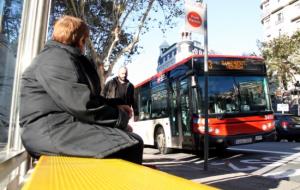 Una dona espera l'autobús en una parada del centre de Barcelona.  ACN