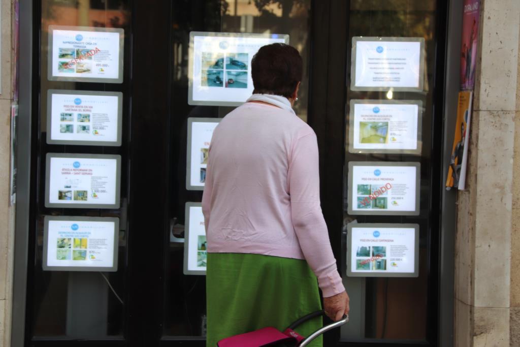 Una dona revisa les ofertes de pisos a la venda fora d'una immobiliària. ACN / Laura Rodríguez