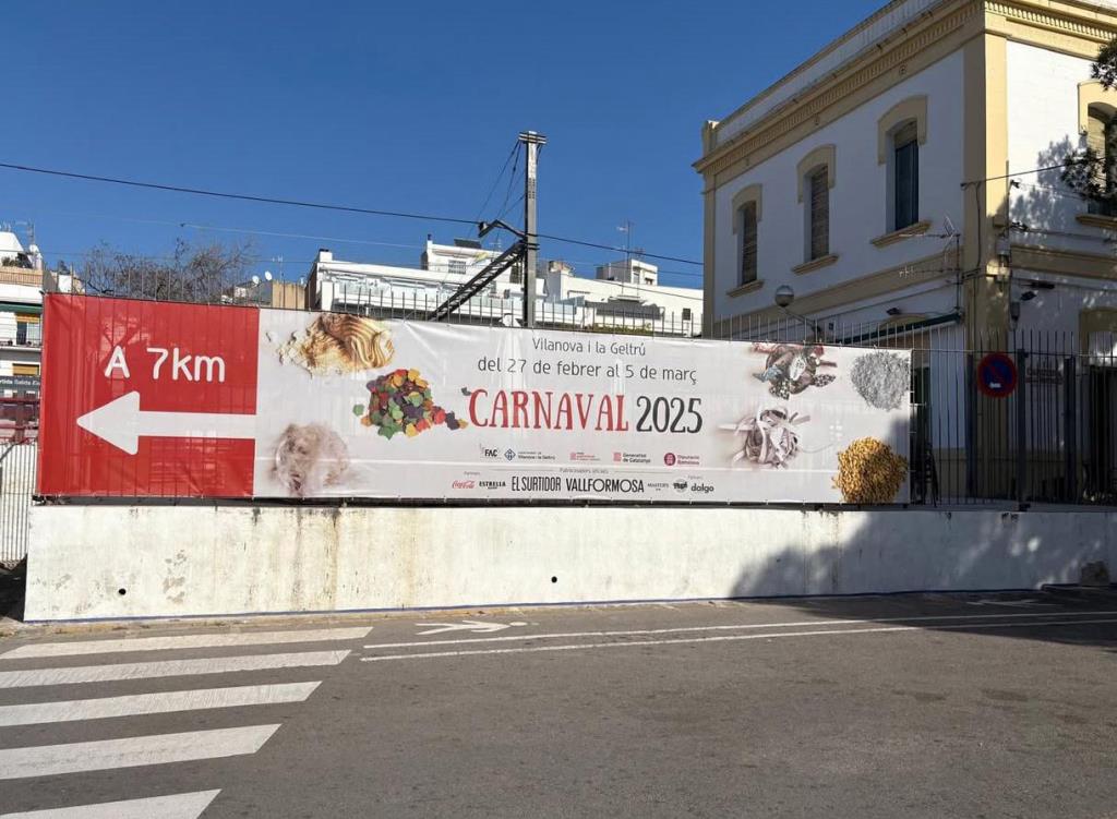 Lona publicitària del carnaval de Vilanova i la Geltrú a l'estació de trens de Sitges. Eix